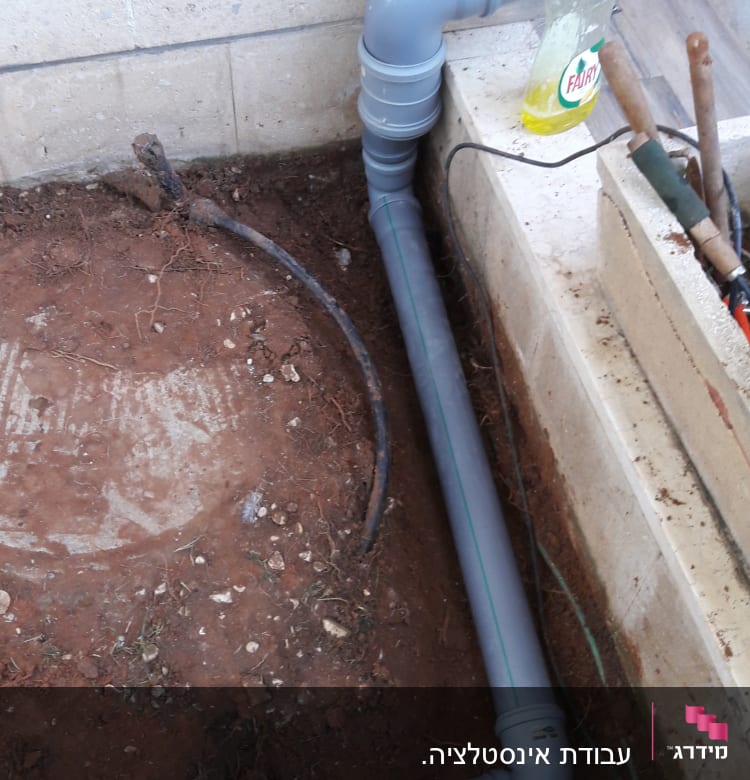 צינור פלסטיק אפור מותקן ליד קיר בטון